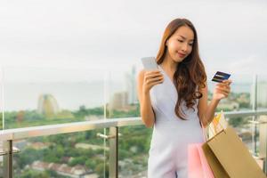 ritratto bella giovane donna asiatica felice e sorridente con carta di credito e cellulare o smart phone e shopping bag