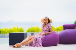 ritratto bella giovane donna asiatica che guarda l'oceano mare con un sorriso felice per rilassarsi il tempo libero in vacanza foto
