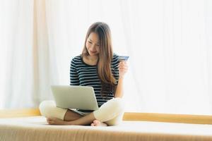 ritratto bella giovane donna asiatica che utilizza computer notebook o laptop con carta di credito per lo shopping foto