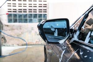 specchietto laterale dell'auto ravvicinato con schiuma per lavaggio auto