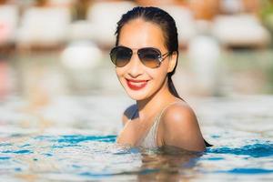 ritratto giovane bella donna asiatica sorriso felice e relax in piscina intorno all'hotel resort foto