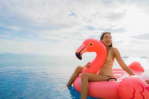 Ritratto di giovane donna asiatica sul fenicottero galleggiante gonfiabile intorno alla piscina all'aperto in hotel resort foto