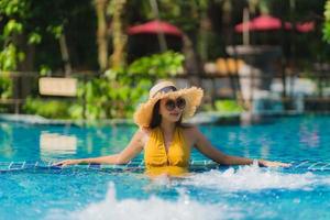 ritratto bella giovane donna asiatica per il tempo libero relax sorriso e felice intorno alla piscina in hotel resort foto