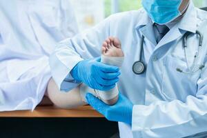 avvicinamento mano indossare medico guanti medico esamina il gamba di il donna plantare, osteofita foto
