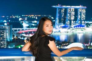 le belle donne asiatiche sorridono e sono felici con la vista della città di Singapore foto