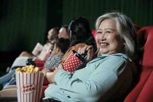 contento persone godere Guardando commedia cinema nel film teatri. anziano asiatico donna e pubblico avere un' divertimento interno divertimento stile di vita con film arte Spettacoli e allegro sorrisi con bevanda e Popcorn. foto