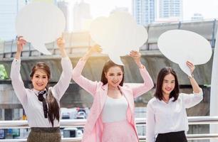 gruppo donne d'affari asiatiche indossano abiti formali alzano cartelli bianchi nel centro della città foto