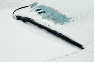 spazzola del tergicristallo congelata sul parabrezza dell'auto - mattina d'inverno che pulisce l'auto da neve e ghiaccio