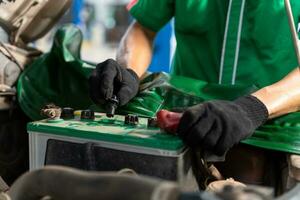 vicino su mano di auto meccanico è di per riparazione batteria per il i clienti chi venire per uso il batteria sostituzione servizio a il negozio. foto