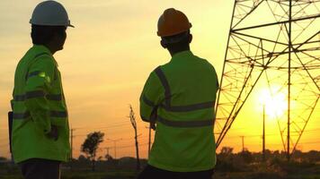 silhouette di ingegnere squadre guardare discutere Piano. Due ingegnere in piedi su campo con elettricità torri a tramonto. foto