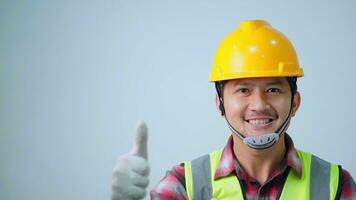 asiatico giovane ingegnere indossare un' giallo sicurezza occhiali e sicurezza veste. guardare per il lato e sorridente. foto