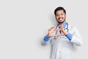 segno del cuore mostrato da un medico pakistano maschio, isolato su bianco foto