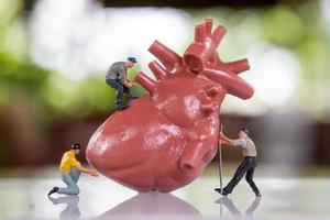 il team di lavoratori in miniatura esamina il cuore ascolta un battito cardiaco e fa una diagnosi foto