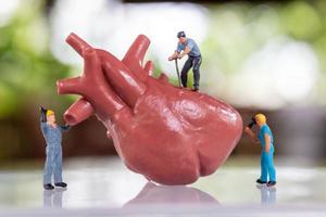il team di lavoratori in miniatura esamina il cuore ascolta un battito cardiaco e fa una diagnosi foto