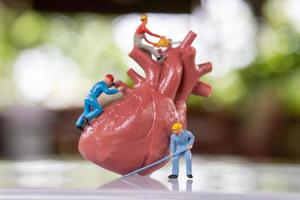 il team di lavoratori in miniatura esamina il cuore ascolta un battito cardiaco e fa una diagnosi foto