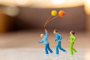 persone in miniatura famiglia felice che corre e gioca con il palloncino foto