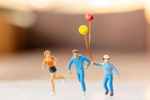 persone in miniatura famiglia felice che corre e gioca con il palloncino foto