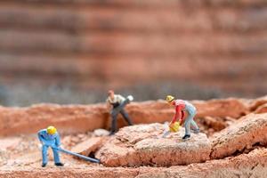 squadra di lavoratori in miniatura che fissa i mattoni durante la costruzione di una casa foto