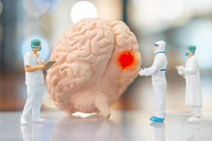 persone in miniatura medico e infermiere che osservano e discutono del cervello umano