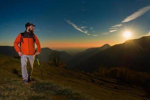 il giovane con la barba che guarda il panorama sta riposando durante un trekking di nordic walking
