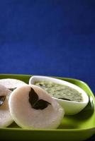 idli con chutney di cocco su sfondo blu, piatto indiano cibo preferito del sud indiano rava idli o semolino pigramente o rava pigramente, servito con sambar e chutney di cocco verde. foto