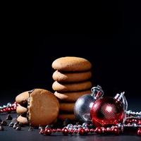 biscotti - pila di deliziosi biscotti alla crema ripieni di crema al cioccolato decorati con ornamenti natalizi su sfondo nero