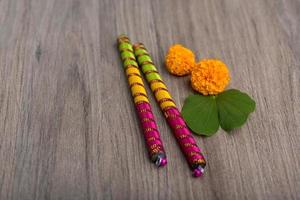 festival indiano dussehra e navratri, che mostra foglie d'oro bauhinia racemosa e fiori di calendula con bastoncini dandiya su uno sfondo di legno foto