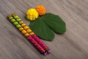 festival indiano dussehra e navratri, che mostra foglie d'oro bauhinia racemosa e fiori di calendula con bastoncini dandiya su uno sfondo di legno foto