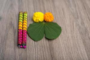 festival indiano dussehra e navratri, che mostra foglie d'oro bauhinia racemosa e fiori di calendula con bastoncini dandiya su uno sfondo di legno foto