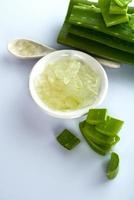 fette di foglie di aloe vera e gel di aloe vera in una ciotola su uno sfondo bianco. l'aloe vera è una medicina erboristica molto utile per la cura della pelle e dei capelli. foto