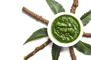 foglie medicinali di neem con pasta in ciotola e ramoscelli su sfondo bianco foto