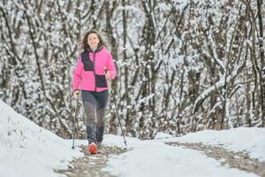 un' giovane donna passeggiate nel nevoso sentiero foto