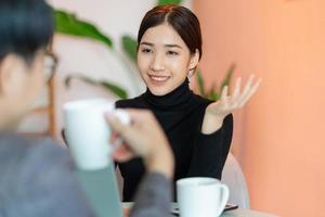 donna asiatica seduta e chiacchierando con i colleghi nella caffetteria dopo il lavoro foto