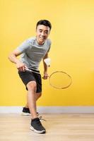 uomo asiatico che gioca a badminton su sfondo giallo foto