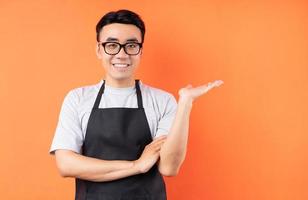 ritratto di cameriere maschio asiatico in posa su sfondo arancione foto