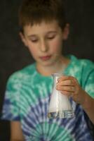 un' ragazzo conduce un' scientifico chimico sperimentare con liquido azoto. un' bambino con un' bicchiere borraccia pieno con Fumo. foto