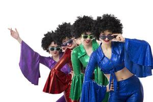 un' gruppo di ragazze nel colorato svasato tute e afro parrucche posa contro un' bianca sfondo. discoteca stile a partire dal il anni ottanta o anni settanta. foto