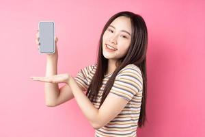 giovane donna asiatica che utilizza smartphone su sfondo rosa foto