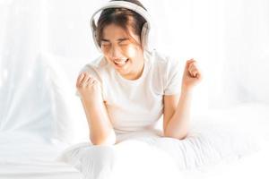 giovane ragazza seduta a letto ascoltando musica divertente foto
