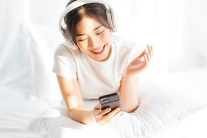 giovane ragazza seduta a letto ascoltando musica divertente