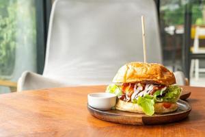 hamburger di manzo con formaggio e salsa su piatto di legno foto