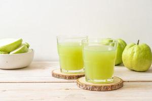 bicchiere di succo di guava fresco con frutta fresca di guava sul tavolo di legno foto