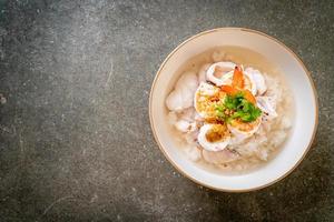 zuppa di porridge o riso bollito con frutti di mare di gamberi, calamari e pesce in una ciotola foto