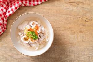zuppa di porridge o riso bollito con frutti di mare di gamberi, calamari e pesce in una ciotola