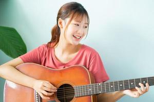 giovane donna asiatica che impara la chitarra a casa?