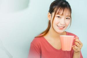 la giovane donna asiatica beve il caffè al mattino?