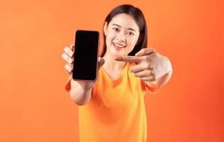 giovane donna asiatica che tiene smartphone con schermo vuoto