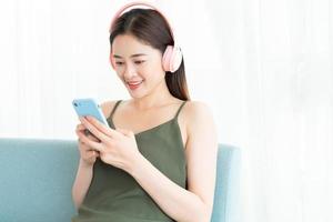 la donna asiatica indossa un auricolare e usa il telefono foto