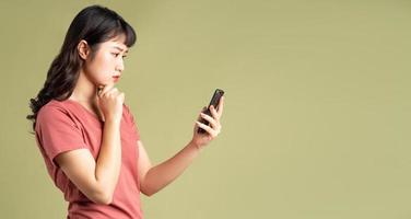 la donna asiatica stava fissando il telefono con un'espressione pensierosa foto