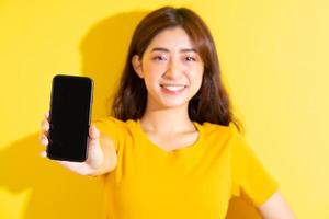 giovane ragazza asiatica che utilizza smartphone su sfondo giallo foto